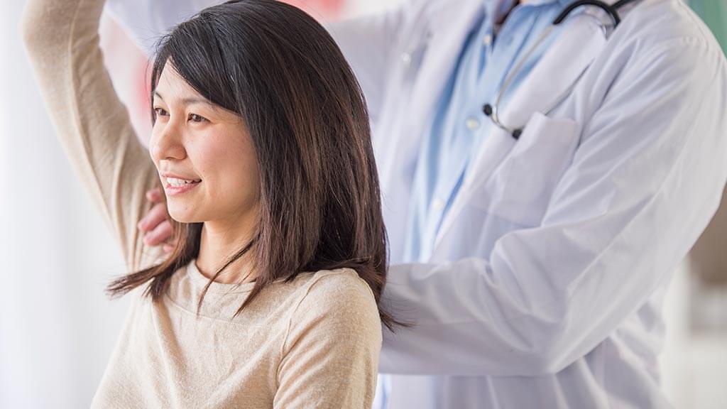 Patient stretching shoulder with doctor's help